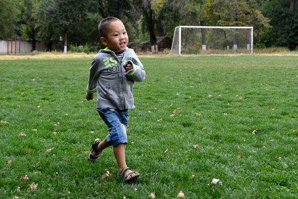 A boy runs in a soccer field while he plays.