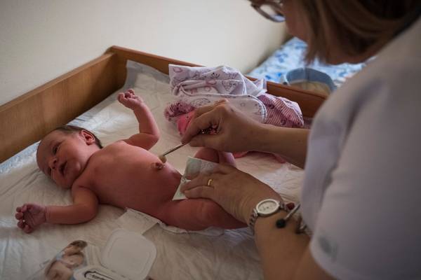 A nurse cleans the umbilical stump of a newborn baby