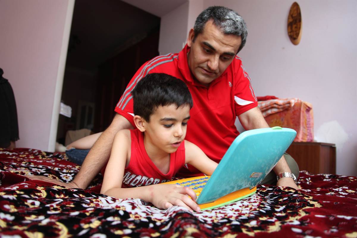 Boy and father sharing screen time.