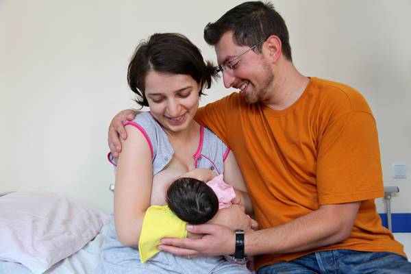 Mama i tata sa novorođenom bebom, mama doji bebu.
