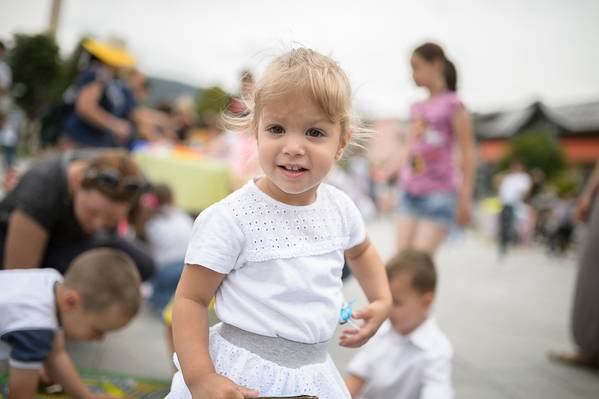 3 year old girl is captured smiling, while attending an outdoor kindergarten.