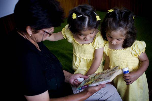 Mother reads for her four-year-old twin foster daughters.