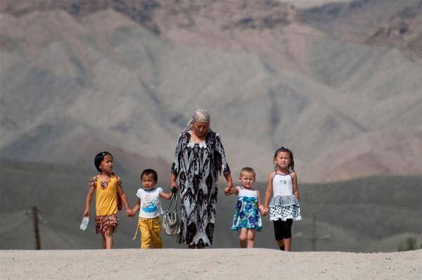 Woman walking hand in hand with her children as they returns home with from the kindergarten.