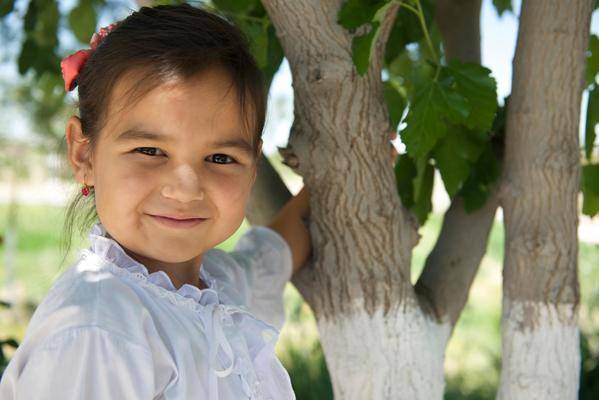 Portrait of girl smiling outside by a tree.
