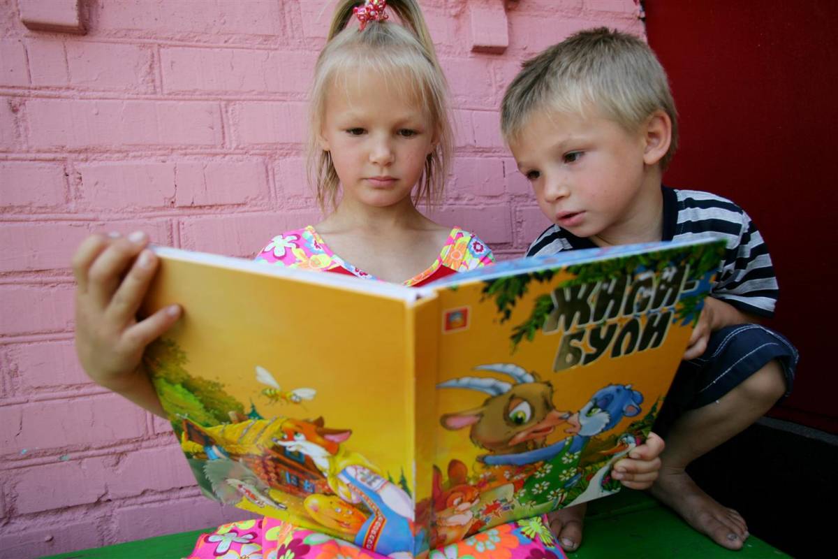 Toddlers reading a yellow book.