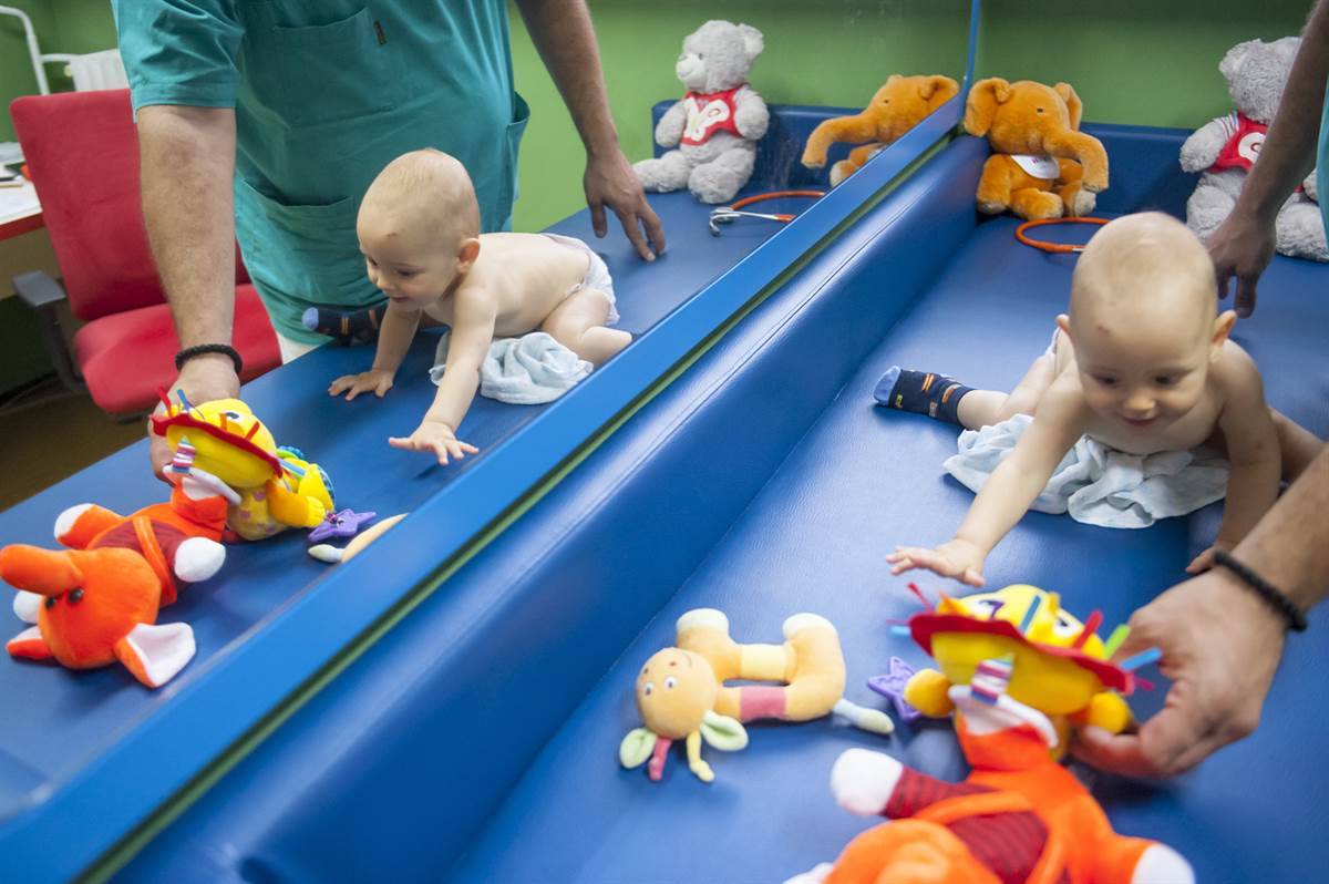 pedijatar provocira puzanje kod bebe igračkama na pultu, u okviru pedijatrijskog preventivnog pregleda