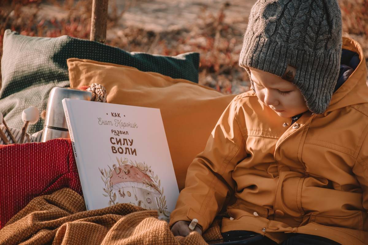 child playing outside reading book