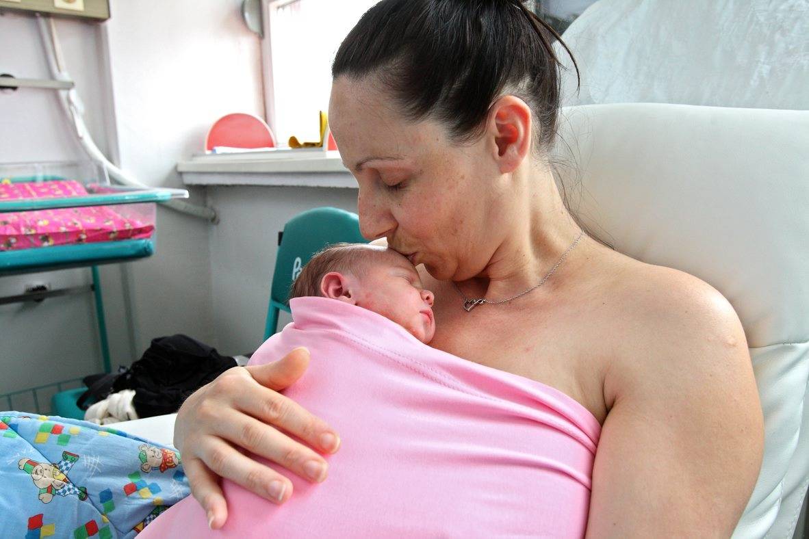 beba leži na grudima mame, začtićena i umotana u bluzu za kontaktu koža na kožu