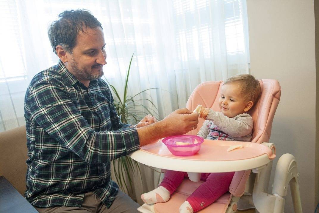 tata i beba koja sedi u stolici za hranjenje, tata kroz komunikaciju podstiče istraživanje i samostalnu ishranu