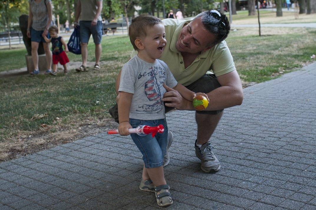 tata i sin smeju se i dogovaraju tata čuči pored deteta detetu da bi ostvario bolji kontakt