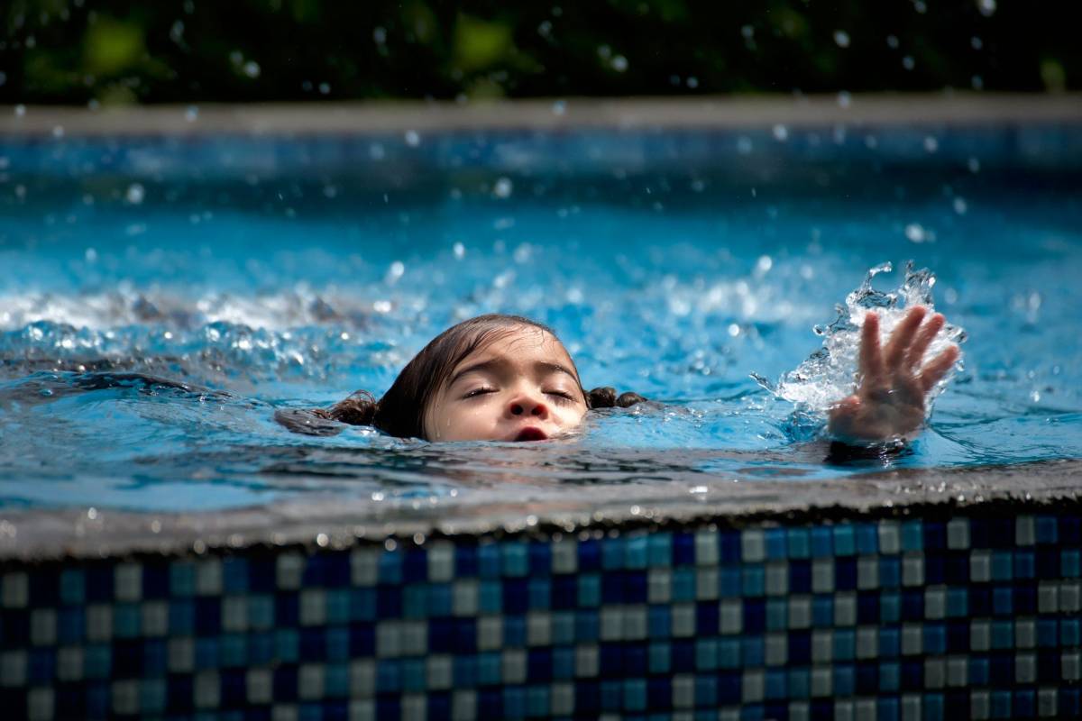 A girl in the pool swallows water and asks for help with her hand