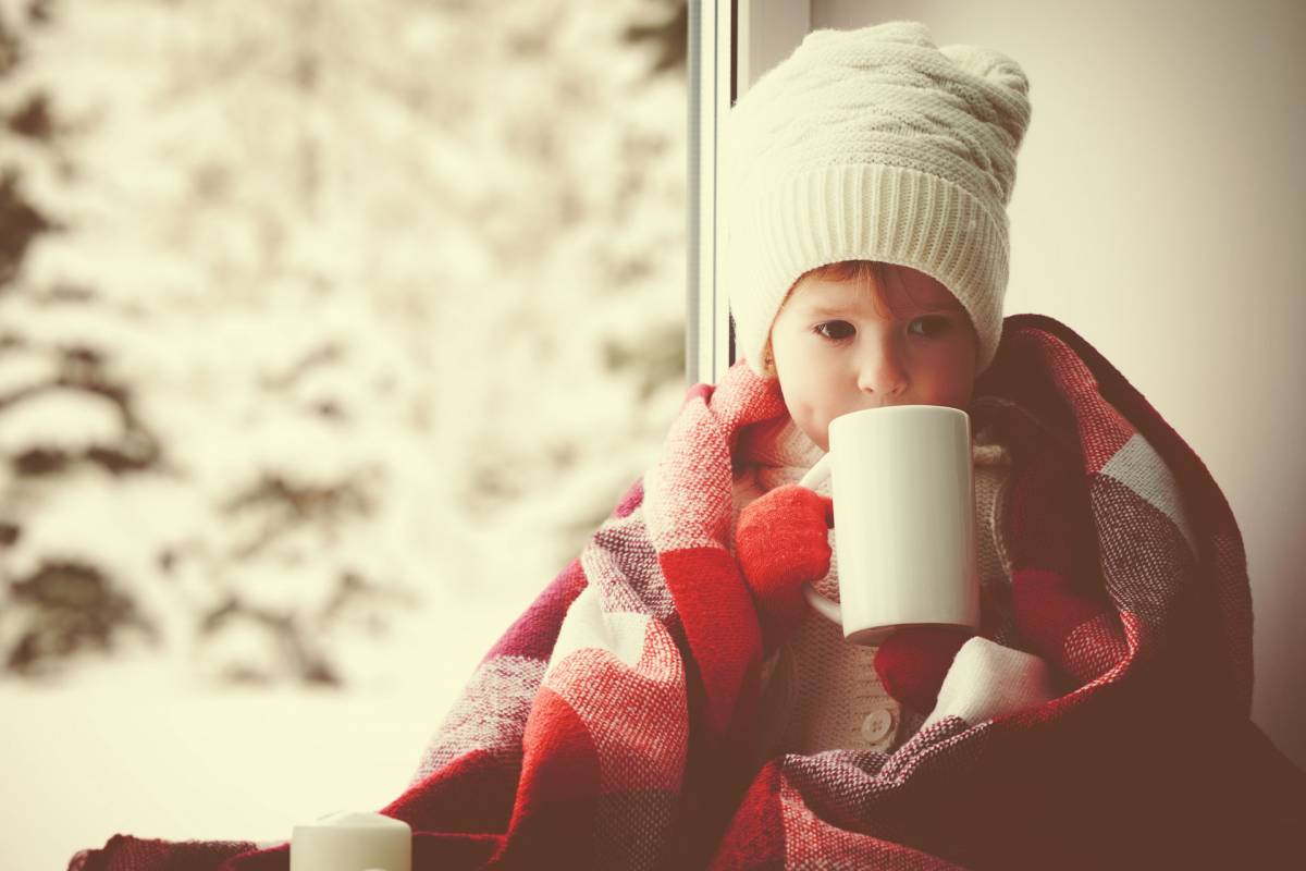 A child wearing a winter clothes with a cup of tea