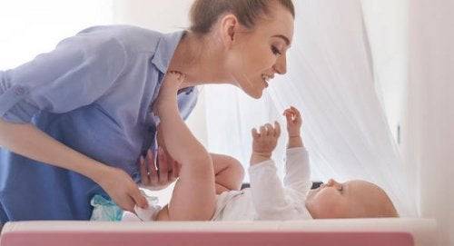 A mother is sinning a song to her child while changing a dipper