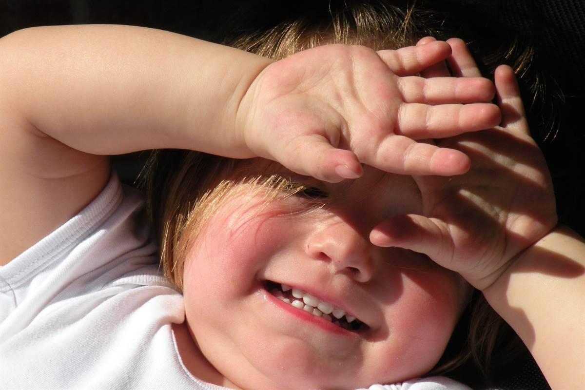 A child covering face with his hands 
