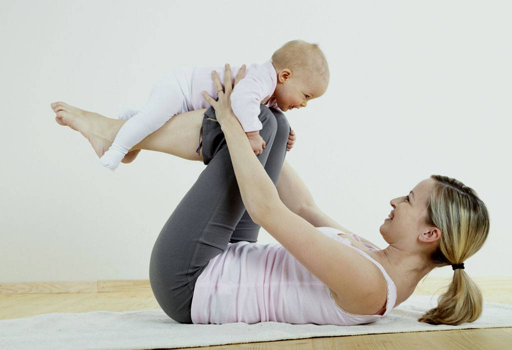 A mother with a baby over her knees imitating flying