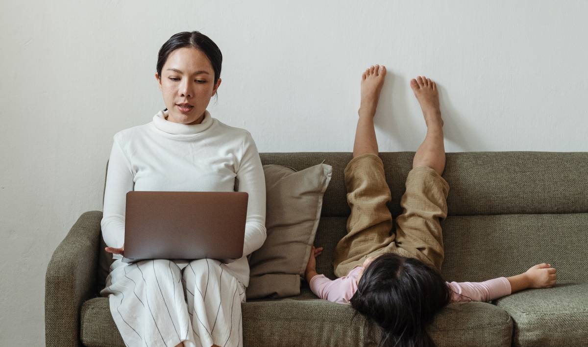 A mother working on her computer while her daughter is around 