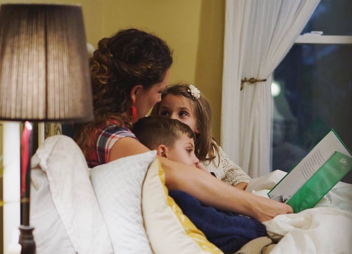 A mother reading a book to her children before going to sleep