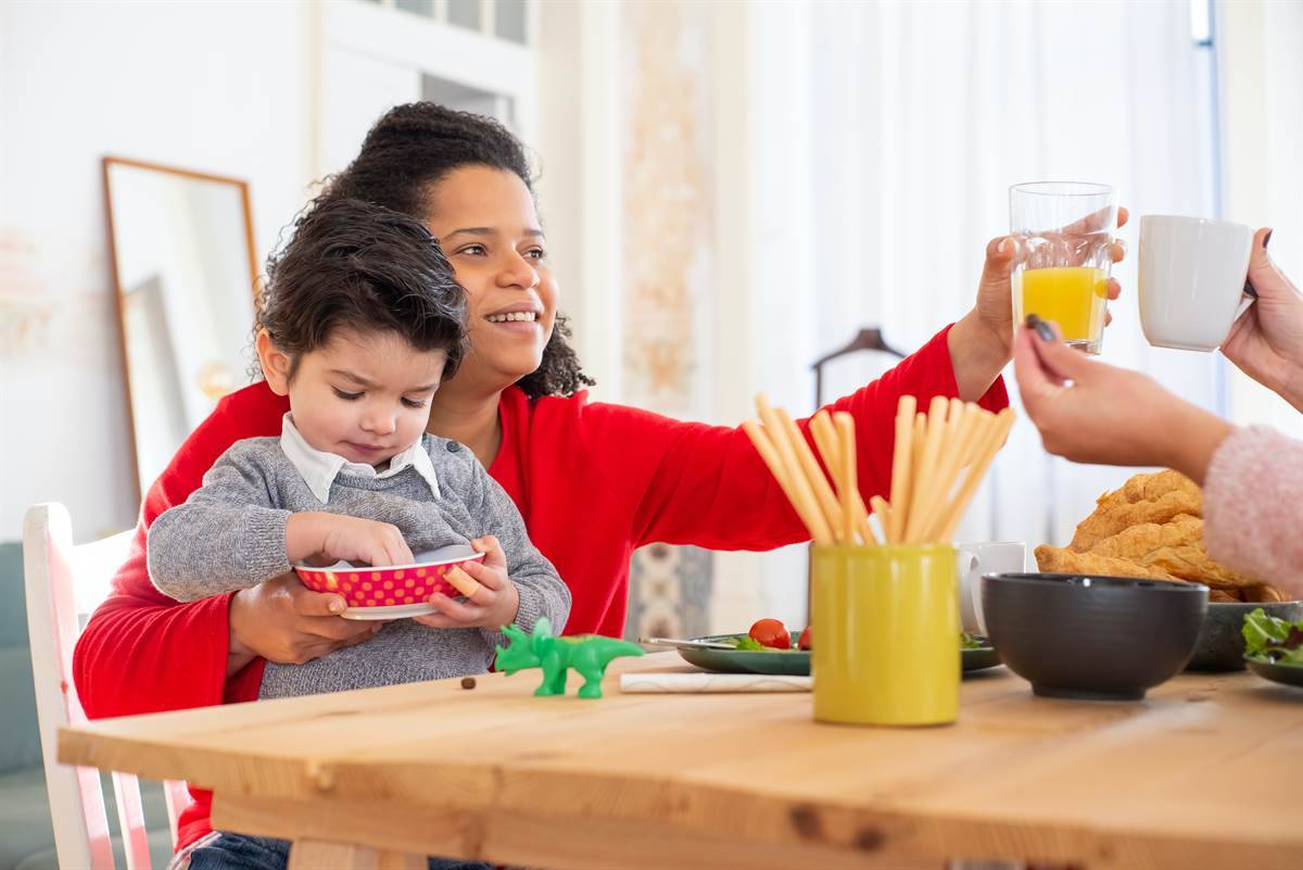 Mother and toddler sitting with family at the dinner table