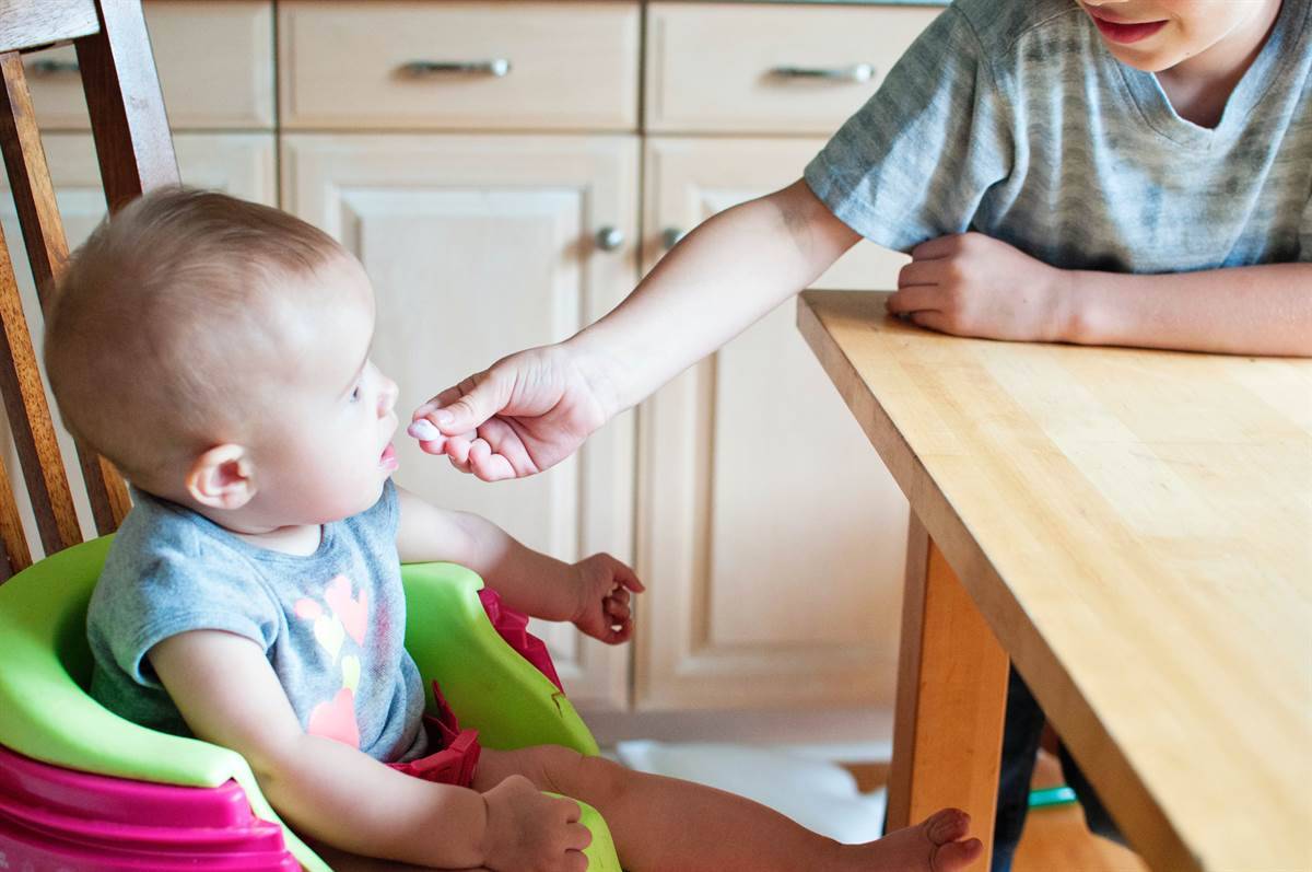 sibling giving baby a sweet