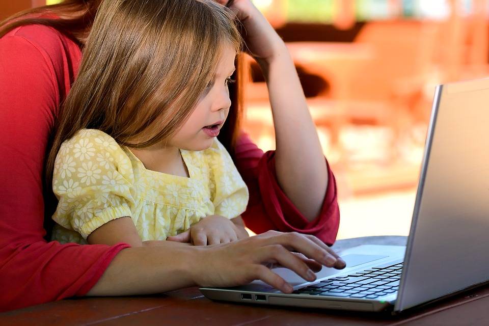 Mother and daughter look at a laptop together