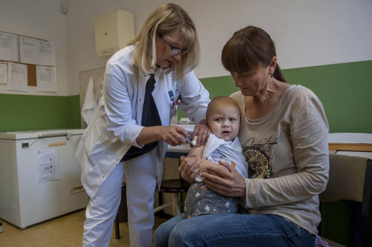 Doctor vaccinating baby sitting on mothers lap
