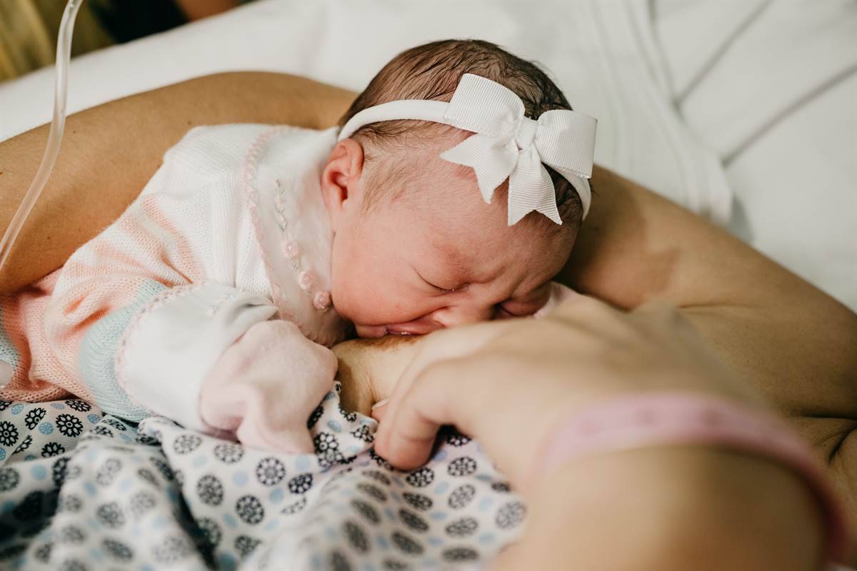Mother breastfeeding newborn daughter in the hospital