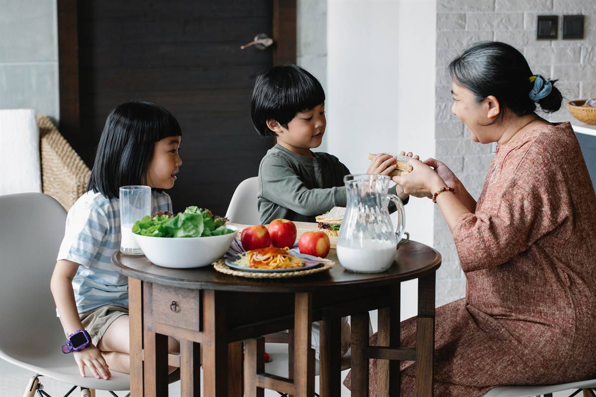 Mother talking to her children at the table filled with healthy food