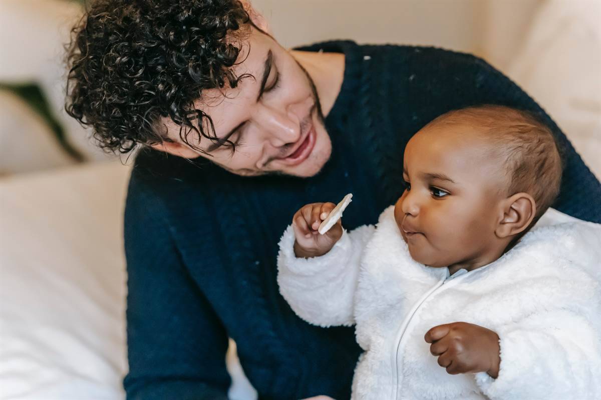 father offering his baby a rice cracker