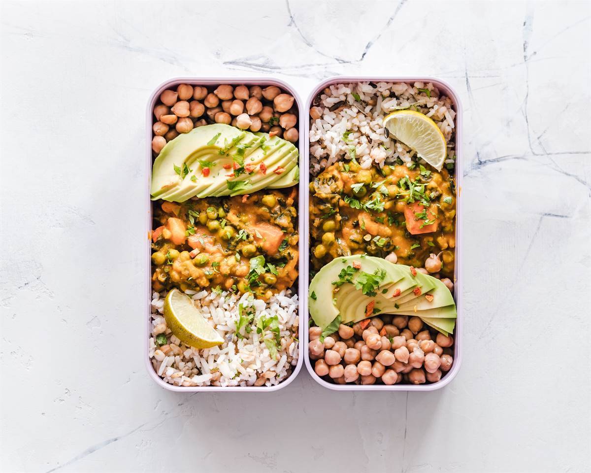lunchboxes filled with curry, beans, lentils, rice and avocado