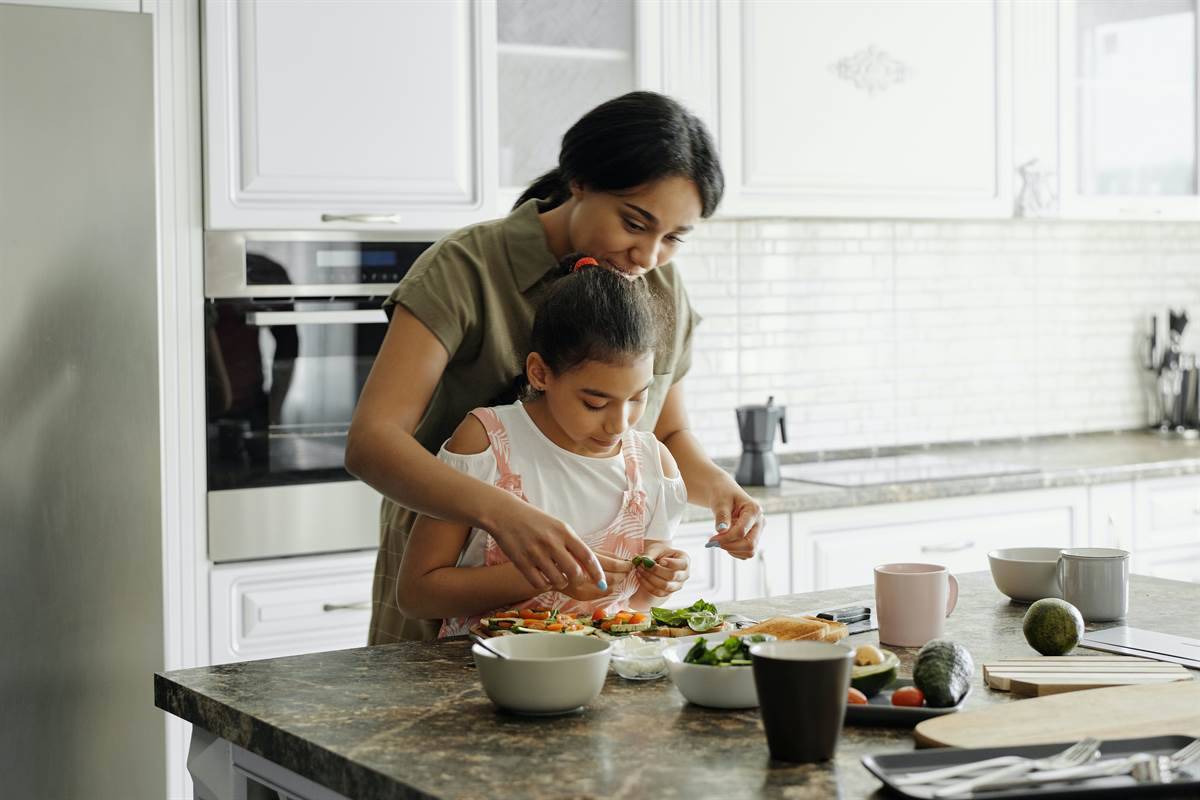 Mother showing her daughter vegetables in the kitchen 