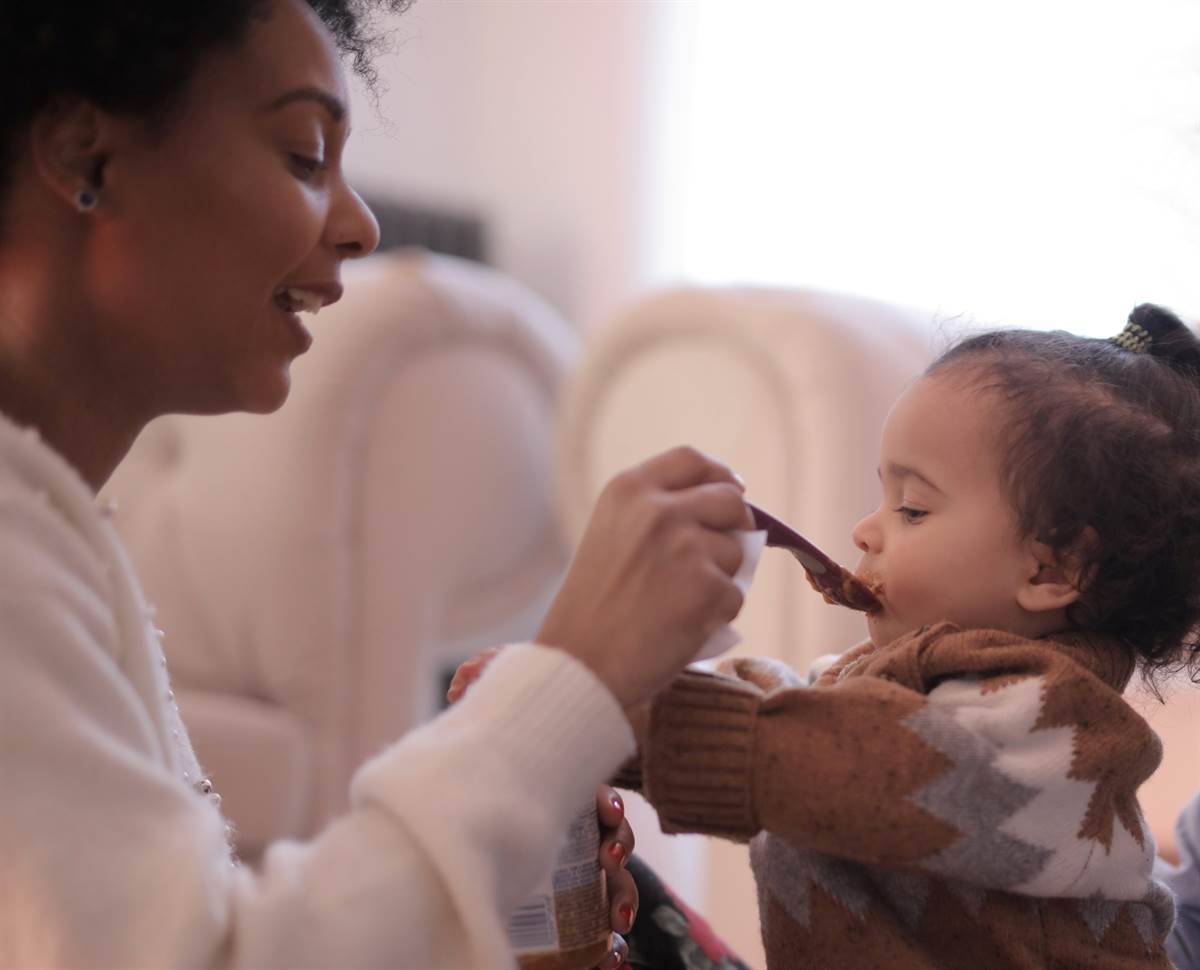 Mother feeding her toddler with a spoon