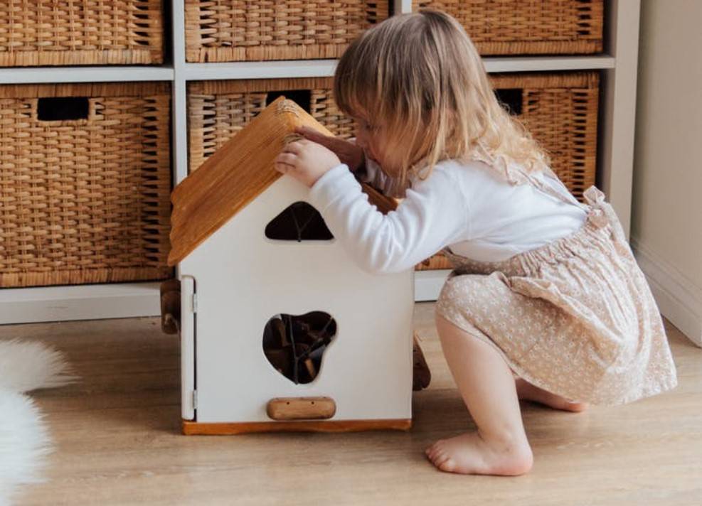child peering into a wooden box with a whole in it
