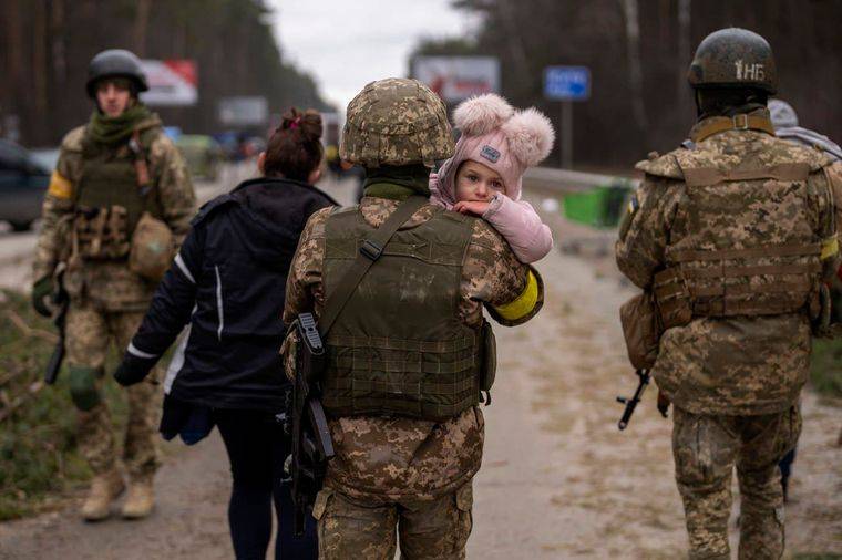 Військовослужбовець несе маленьку дитину на руках