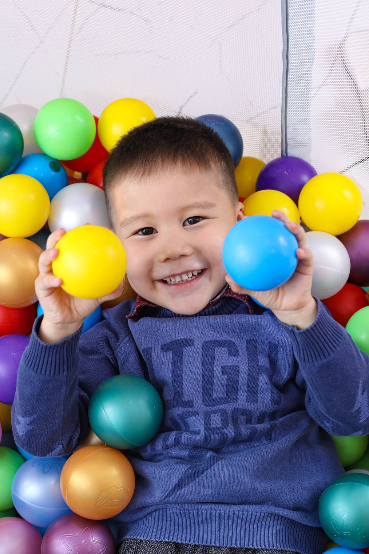 Unicefkg\Ergashev\Маленький мальчик лежит в ярких шариках