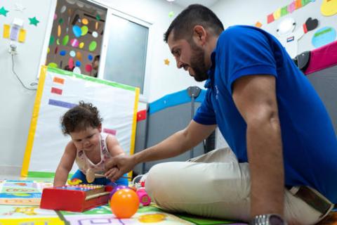 A father is playing the musical instrument with the child