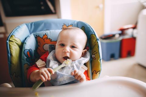 A baby eating with a spoon