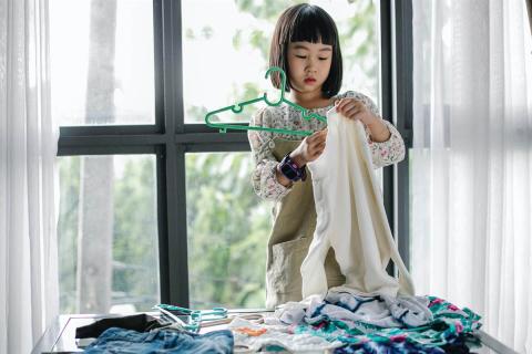 A girl hangs her clothes on a hanger 