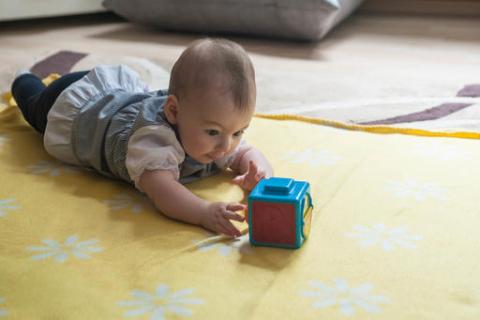 A baby trying to reach out to the box