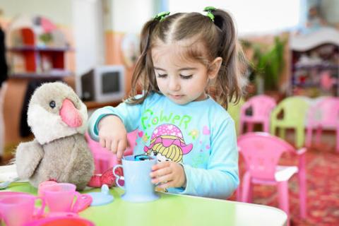 Girl pretending to make a meal for her toys