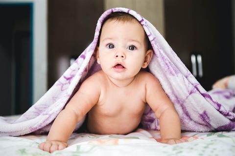 A baby crawling from under the covers