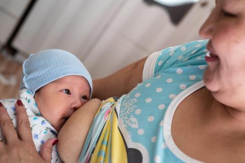 Mother looks at her baby while breastfeeding.