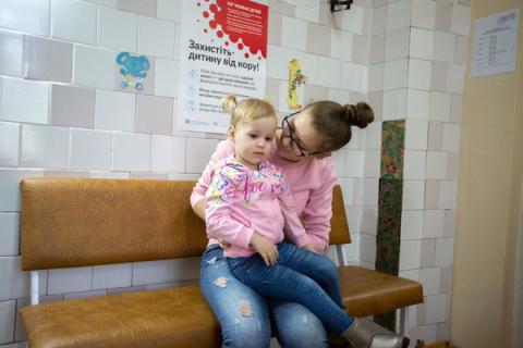 2 years old is held by her mother as she prepares to receive her first MMR vaccination against measles, mumps and rubella in a state polyclinic in the centre of Kyiv, Ukraine