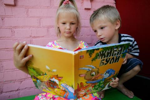 Toddlers reading a yellow book.