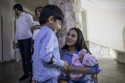 Mother holds her newborn daughter and speaks to her son.