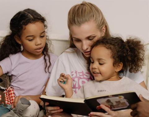A mother looking family photo album with her daughters