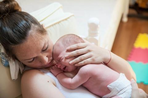 mama drži bebu na grudima i komunicira sa njom, beba se osmehuje i uživa