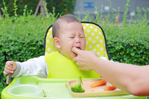 An adult uses her/his finger to remove food from the baby's mouth that can be a potential cause of suffocation