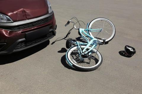 A bicycle and a helmet next to a damaged car