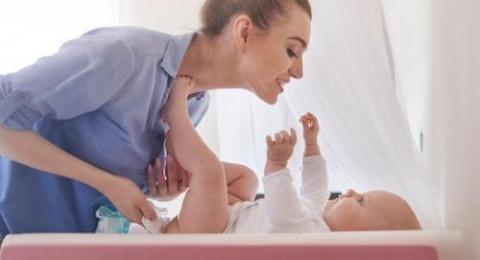 A mother is sinning a song to her child while changing a dipper
