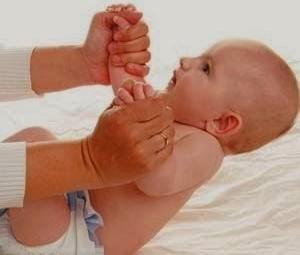 A baby trying to sit up with the help of her/his mother